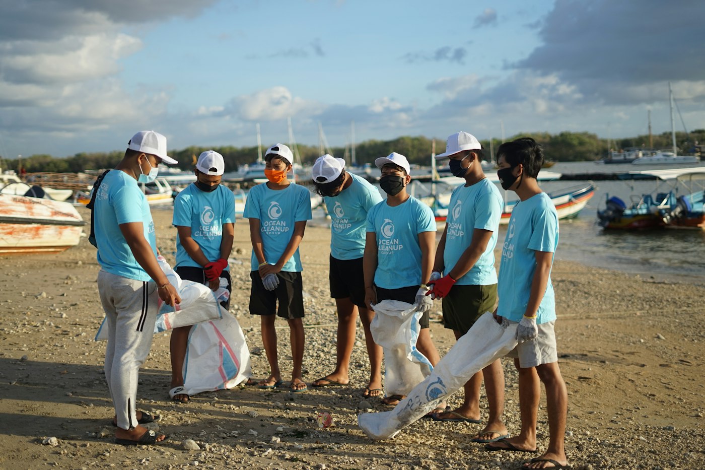 Volunteers in matching shirts holding bags during a shoreline cleanup